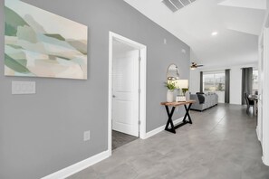 A hallway with a modern design, featuring a grey wall, a white door, and a light switch. - Star Wars Game Room | Treehouse | Near Disney 9092 (Davenport)