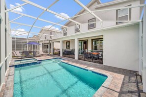 Ein Poolbereich mit Glasveranda, Liegestühlen und Essbereich mit Gartenmöbeln.