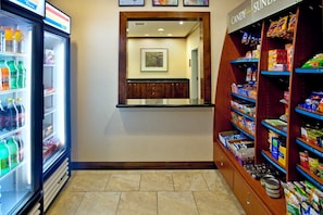 A hotel lobby with a vending machine, a candy shelf, and a framed artwork on the wall.