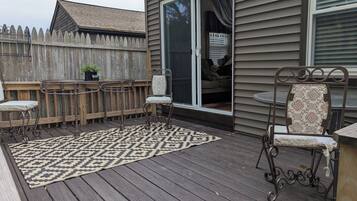 A deck with a patterned rug, metal chairs, and a table.