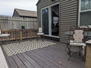 Una terrazza con un tappeto decorato, sedie in metallo e un tavolo.