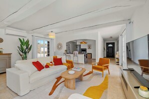 Un'ampia zona giorno con un divano bianco, un tavolino in legno e un tappeto dai colori vivaci.