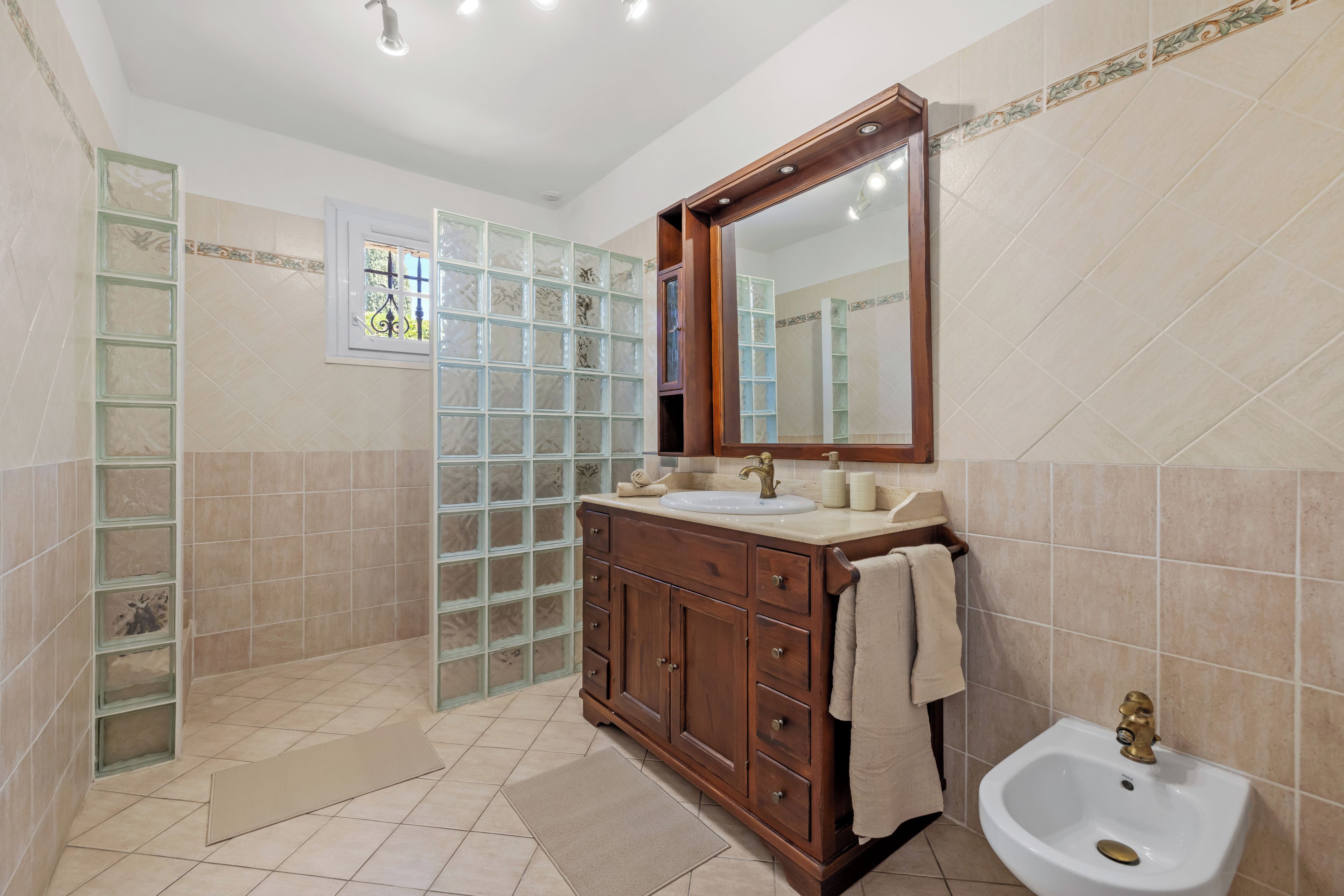 A bathroom with a wooden vanity, a sink, a mirror, and a shower area with glass doors.