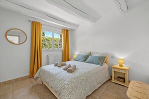 Una camera da letto con un letto, un comodino con una lampada, una finestra con tende e un termosifone.