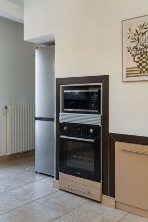 Une cuisine compacte équipée d’un four encastré, d’un réfrigérateur et d’un four à micro-ondes.
