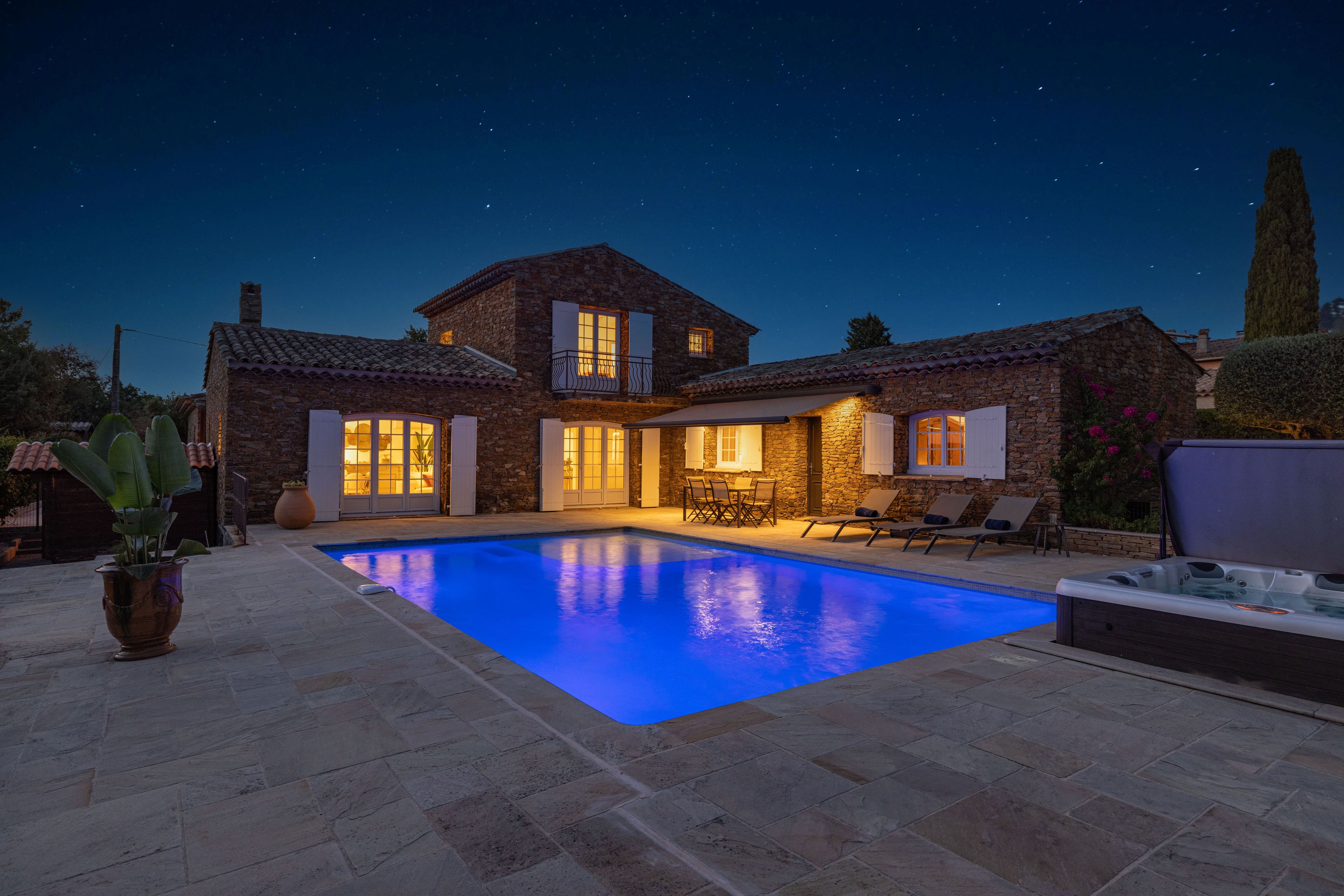 A stone house with a swimming pool, outdoor seating, and a hot tub.