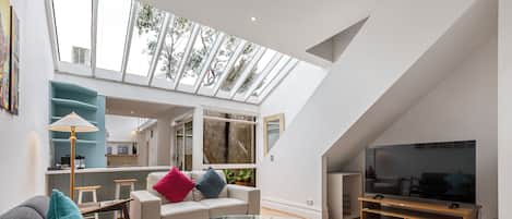 A modern living room with a glass coffee table, a sofa, and a television.