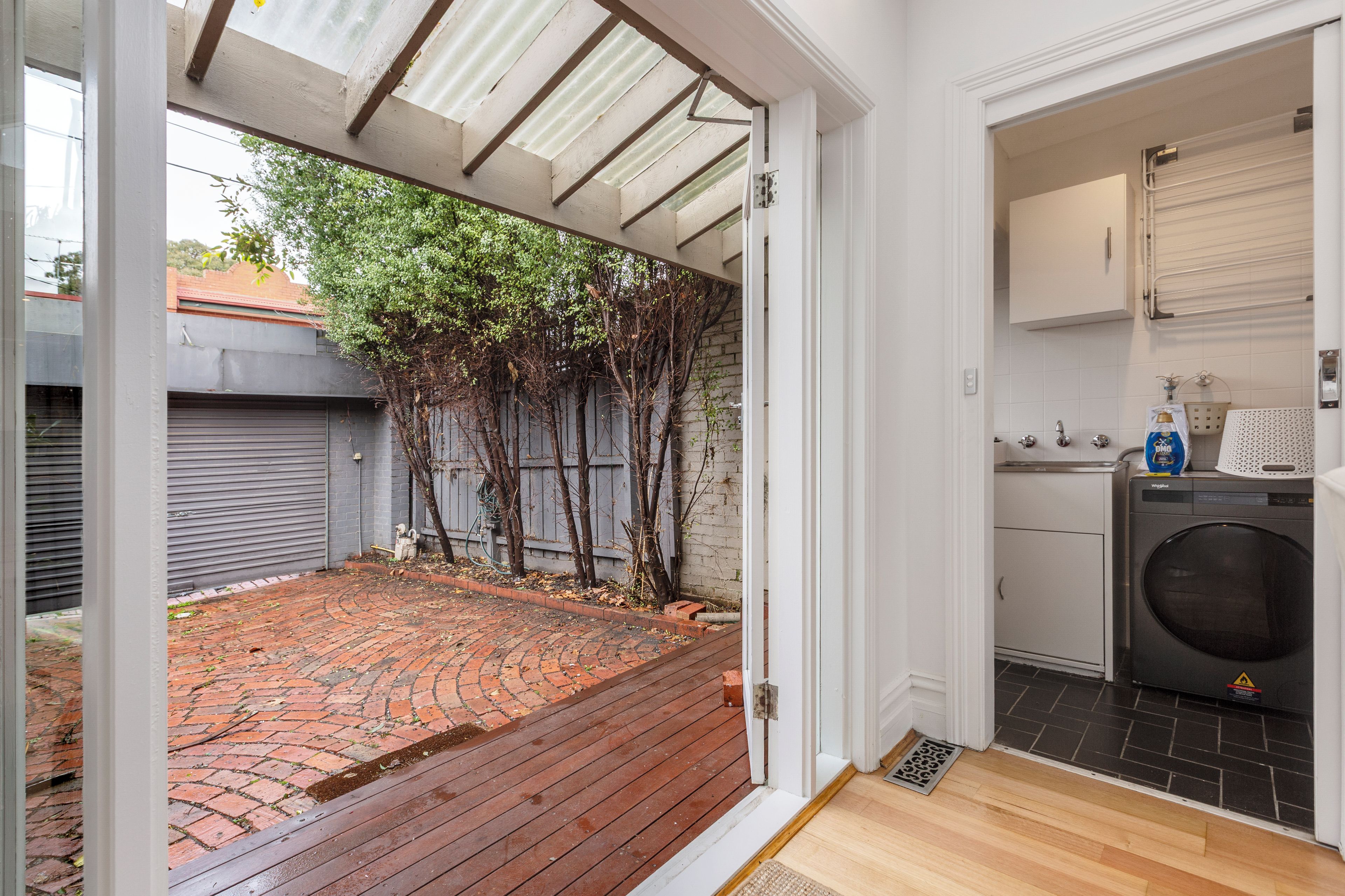 A laundry room with a washing machine, a drying rack, and a small sink.