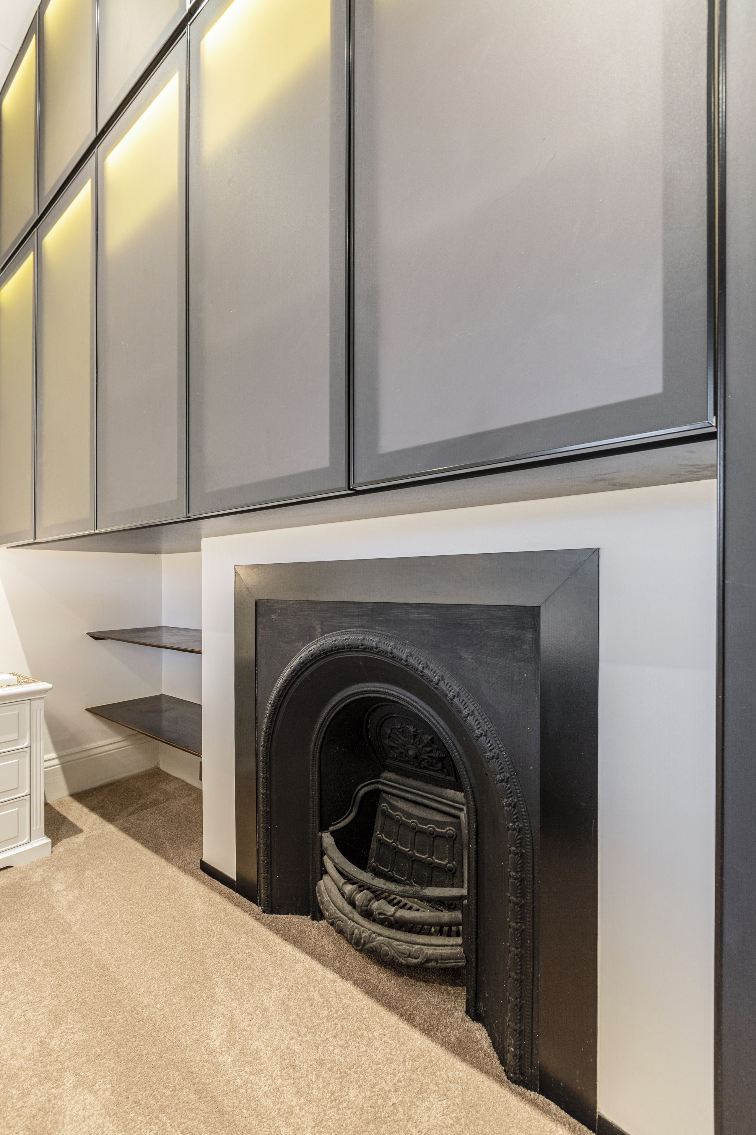 A modern interior with a fireplace, built-in shelves, and a staircase.