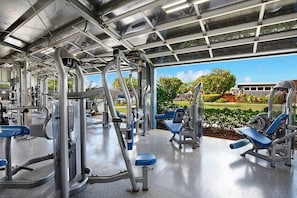 Ein Fitnessstudio mit verschiedenen Trainingsgeräten und Blick auf eine grüne Landschaft.