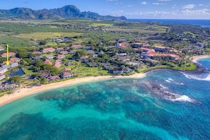 Eine Luftaufnahme einer Küstenwohngegend mit Häusern, einem Strand und klarem, blauem Wasser.