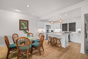 A modern kitchen with white cabinetry, a central island, and pendant lighting. - Kiahuna Hale Kai II (Koloa)