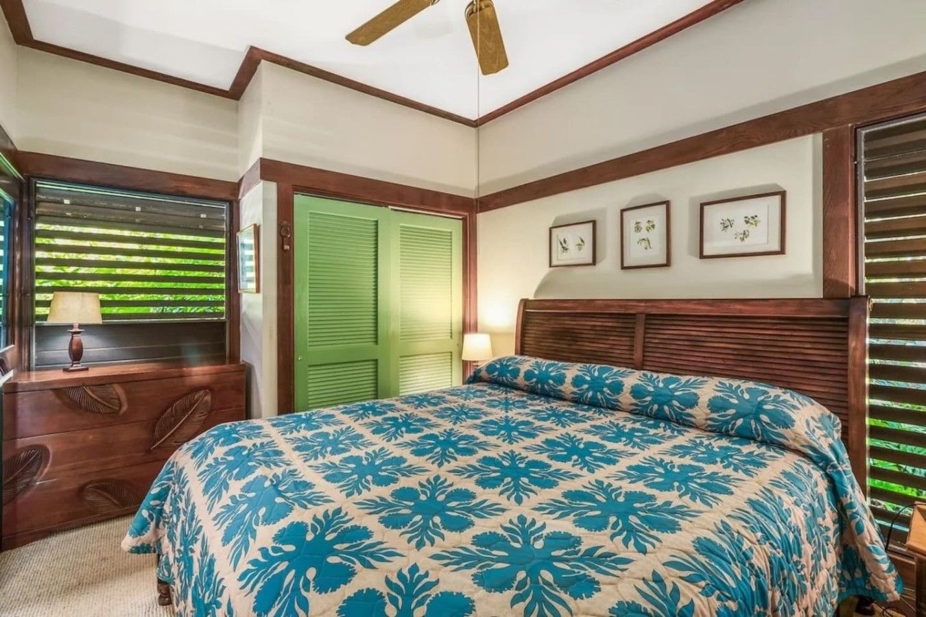 A bedroom with a bed, a nightstand, a lamp, a window with blinds, and a green door.