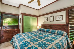 Quarto com cama, mesa de cabeceira, luminária, janela com persianas e porta verde.