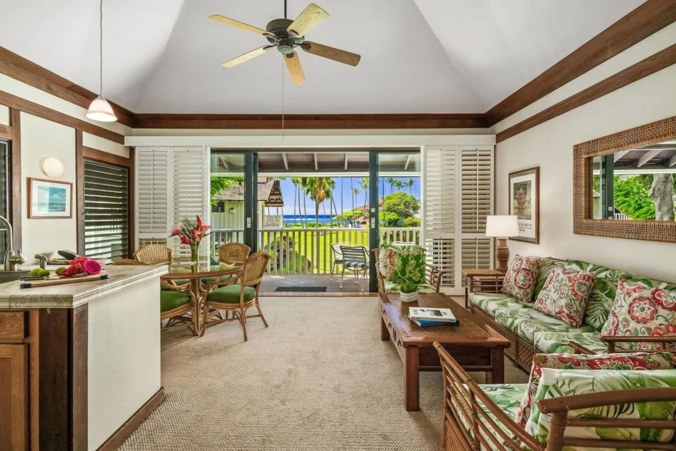 A room with a ceiling fan, a dining area with a table and chairs, a sofa, and a view of the outdoors.
