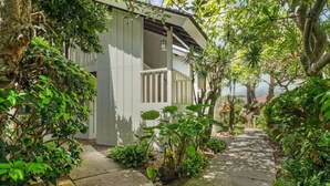 A covered outdoor area with a concrete path leading to a building with a white exterior and a balcony. - Kiahuna Hale Kai III (Koloa)
