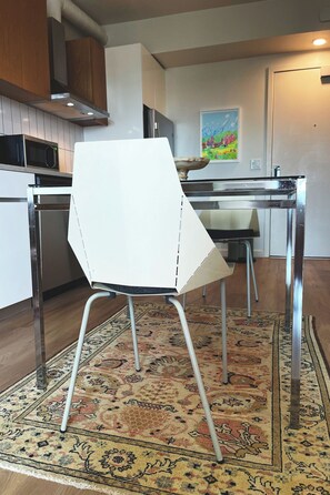 Una cocina moderna con una silla blanca, electrodomésticos de acero inoxidable y un tapete estampado.