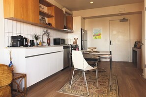 A modern kitchen with white cabinets, a microwave, a coffee maker, and a dining area with a chair and rug. - Top-Floor Hillcrest Penthouse w/ Balcony, Pool & Gym Near Zoo (San Diego)