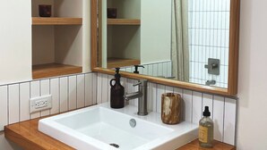 A bathroom with a white sink, wooden countertop, and a large mirror.