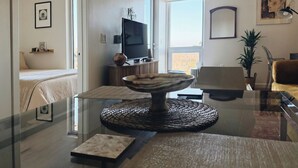 A modern living room with a glass coffee table, a television, and a sofa.