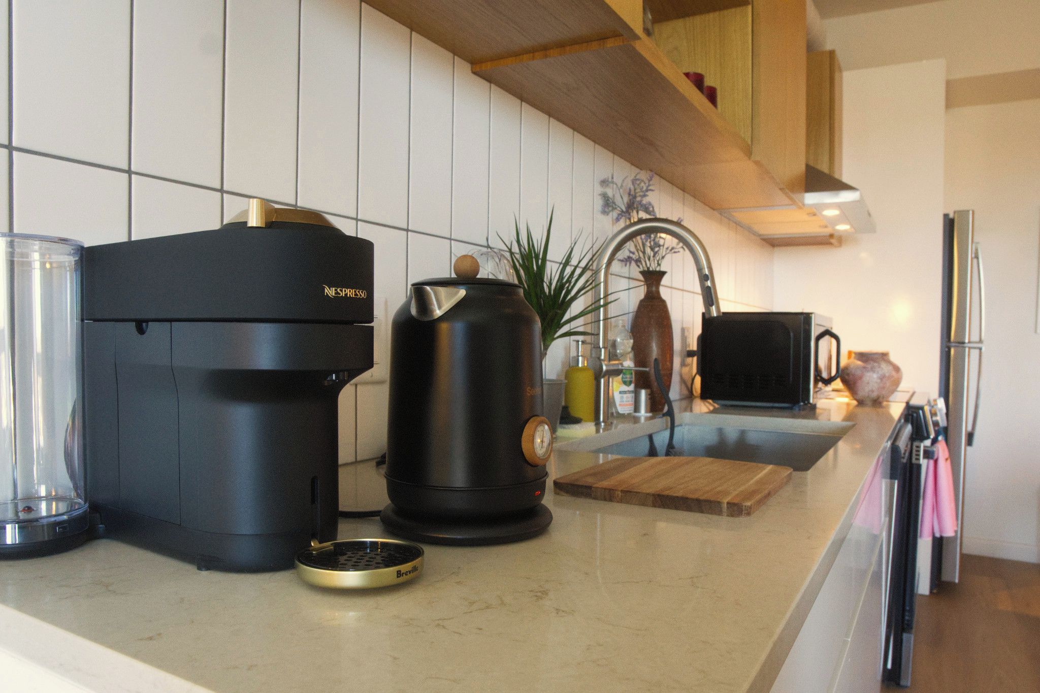 Una cocina moderna con cafetera, hervidor y tostadora sobre la encimera.
