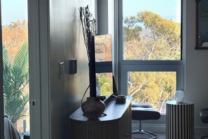 A room with a large window, a vase on a wooden console, a chair, and a small table with a lamp. - Top-Floor Hillcrest Penthouse w/ Balcony, Pool & Gym Near Zoo (San Diego)