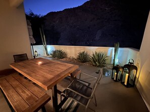 Eine Terrassengruppe im Freien mit Holztisch und Stühlen, umgeben von Pflanzen und einem Kaktus.
