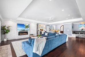 Ein modernes Wohnzimmer mit einem blauen Sofa, einem Kamin und einer Küche im Hintergrund.