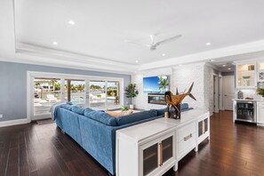 A modern living room with a sectional sofa, a fireplace, and a view of a pool and buildings. - WATERFRONT OASIS-4 BED/3 BATH HOME WITH POOL, SPA, DOCKAGE CLOSE TO DOWNTOWN (St. Petersburg)