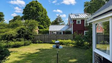 A residential backyard with a bird feeder, a wooden fence, and a house with a red exterior and white trim.