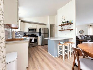 Een moderne keuken met witte kasten, roestvrijstalen apparatuur en een centraal keukenblok met krukken.
