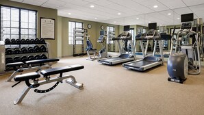 A fitness room with treadmills, elliptical machines, a bench press, and dumbbells. - ADA Suite Near NASA Goddard | Free Breakfast! (Lanham)