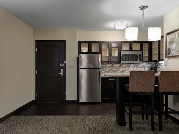 A compact kitchen with a refrigerator, microwave, and dark cabinets.