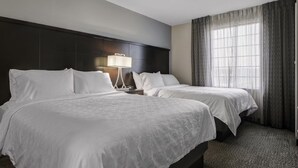 A hotel room with two beds, a dark headboard, a bedside table with a lamp, and a large window with curtains. - ADA Suite Near NASA Goddard | Free Breakfast! (Lanham)