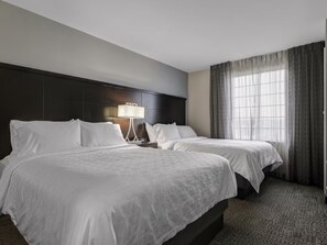 A hotel room with two beds, a dark headboard, a bedside table with a lamp, and a large window with curtains. - ADA Suite Near NASA Goddard | Free Breakfast! (Lanham)