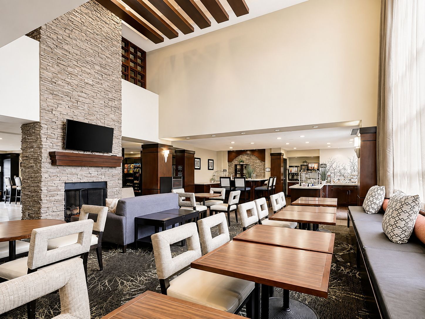 A hotel lobby with a fireplace, seating areas, and a television.