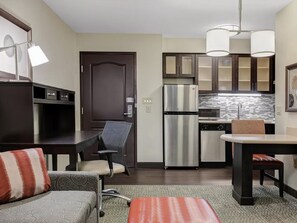 A compact living space with a kitchenette, a dining area, and a seating area with a sofa and chairs.