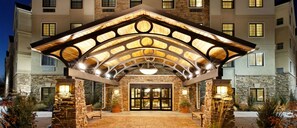 A hotel entrance with a stone facade, a covered entrance area, and a central light fixture.