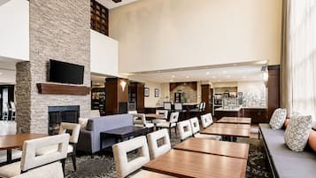 A hotel lobby with a fireplace, seating areas, and a television.
