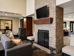 A modern living room with a stone fireplace, a flat-screen TV mounted above it, and a seating area with sofas and armchairs. - ADA Studio Nr Washington D.C. | Free Breakfast! (Lanham)