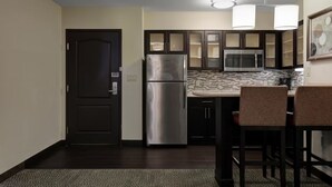 Una cocina compacta con refrigerador, microondas y armarios oscuros.