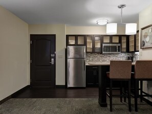 A compact kitchen with a refrigerator, microwave, and dark cabinets. - Hearing Accessible Suite Nr UMD | Free Breakfast! (Lanham)