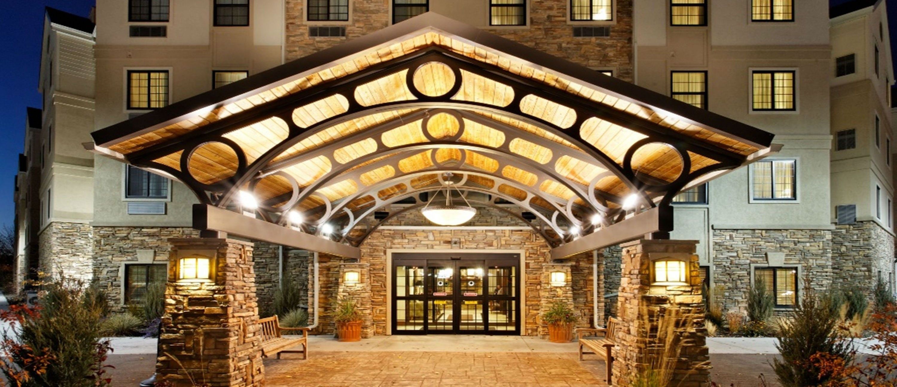 L’entrée d’un hôtel, avec une façade en pierre, un espace d’entrée abrité et un luminaire central.