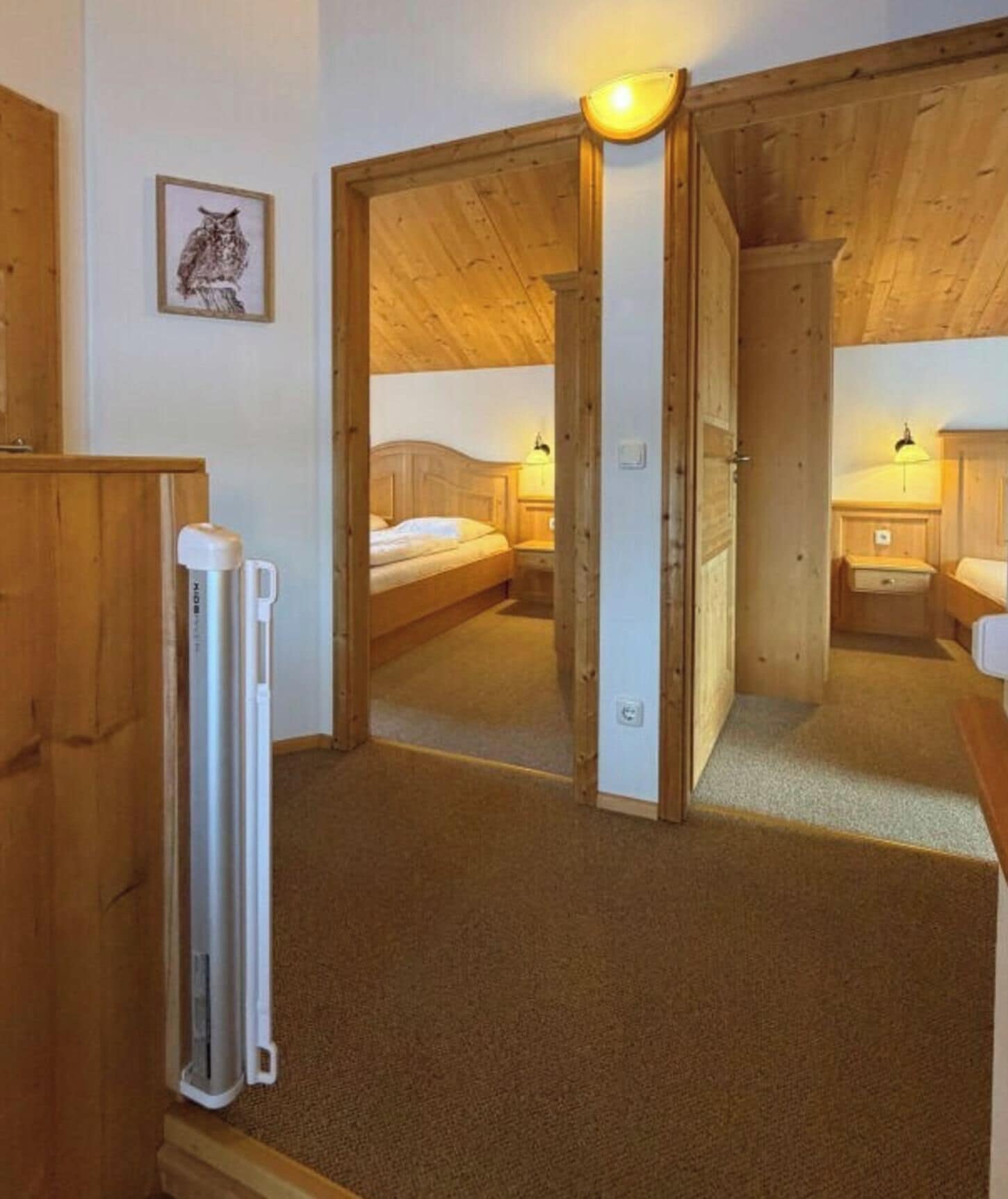A room with a bed, bedside table, and a mirror reflecting the room.