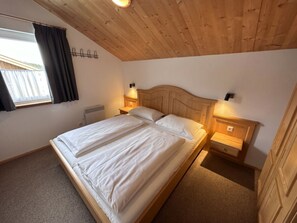 A single bed with a wooden headboard in a room with a sloped ceiling and a window with curtains. - Cabin in Annaberg With Swimming Pool (Annaberg-Lungoetz)
