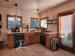A modern kitchen with wooden cabinets, a stainless steel dishwasher, a gas stove, and a trash can. - Cozy 1-bedroom studio in delightful Culver City with AC (Culver City)
