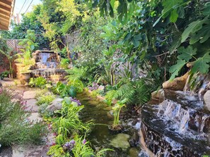 A garden with a small waterfall, lush greenery, and a stone pathway. - Cozy 1-bedroom studio in delightful Culver City with AC (Culver City)