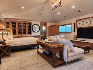 A spacious living room with a large bed, a sofa, a wooden coffee table, and a television. - Cozy 1-bedroom studio in delightful Culver City with AC (Culver City)