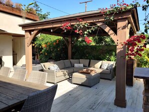 An outdoor patio with a wooden pergola, wicker furniture, and a variety of plants and flowers. - Cozy 1-bedroom studio in delightful Culver City with AC (Culver City)