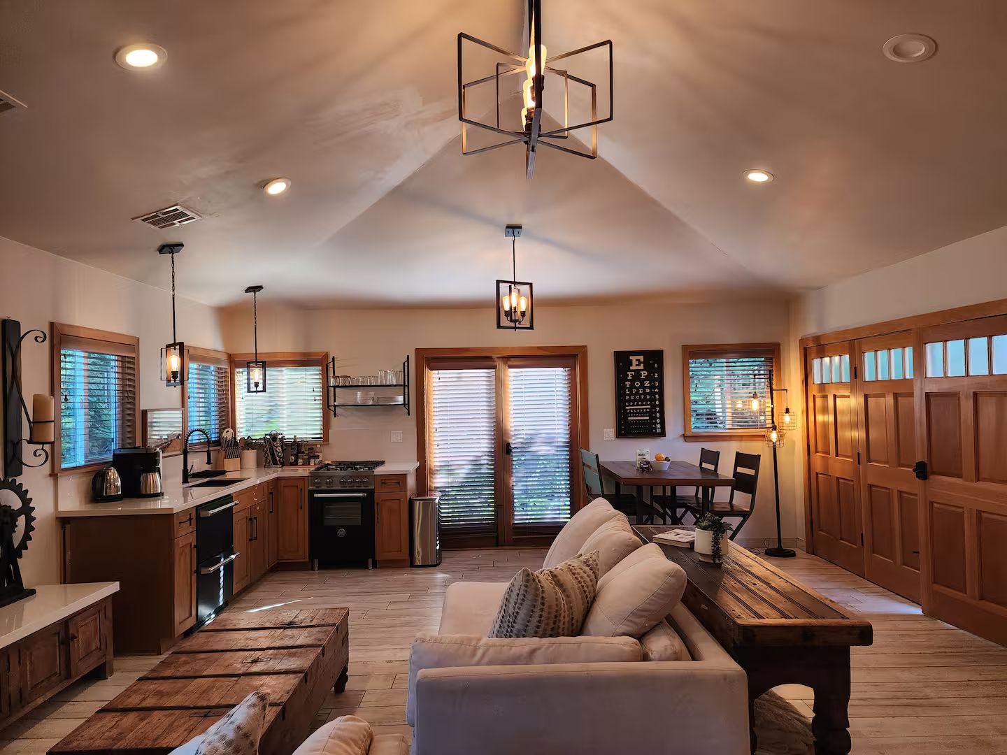 A spacious kitchen with wooden cabinets, a dining area with a bench, and a large window with blinds.